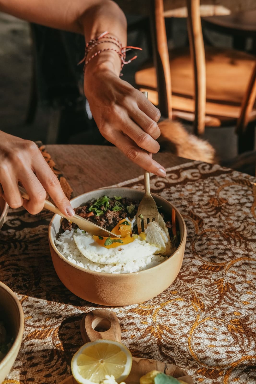 A rice bowl with beef, greens and a fried egg on a patterned cloth at Lulu's cafe.