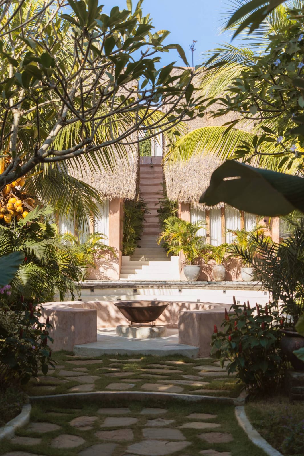 The stone path through the gardens to the fire bowl, with the thatched villas and the stairs beyond.